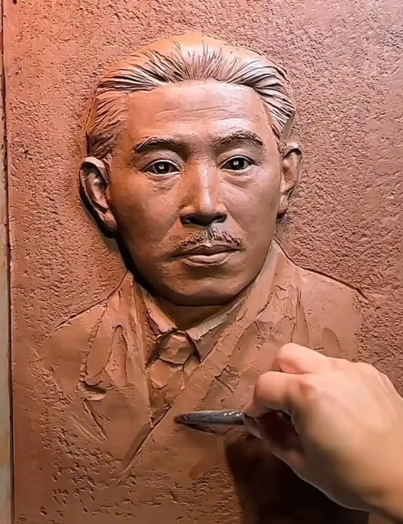 The sculptor adding texture to the custom bronze relief for the Mao Dun Literature Prize, carefully shaping the writer’s period clothing and collar.