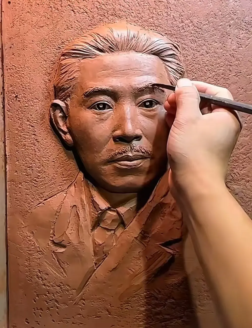 Close-up of the sculptor refining the custom bronze relief for the Mao Dun Literature Prize, capturing the writer’s thoughtful gaze in clay.