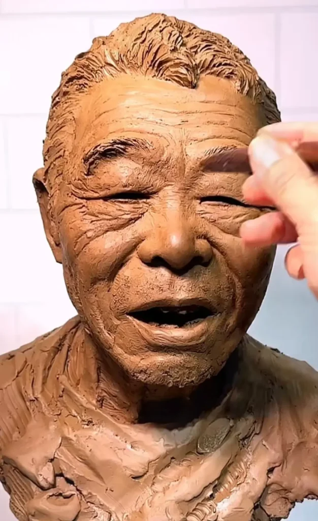 Close-up shot of a sculptor using tools to refine the eyebrows and facial lines of an elderly man’s clay bust, emphasizing lifelike detail work