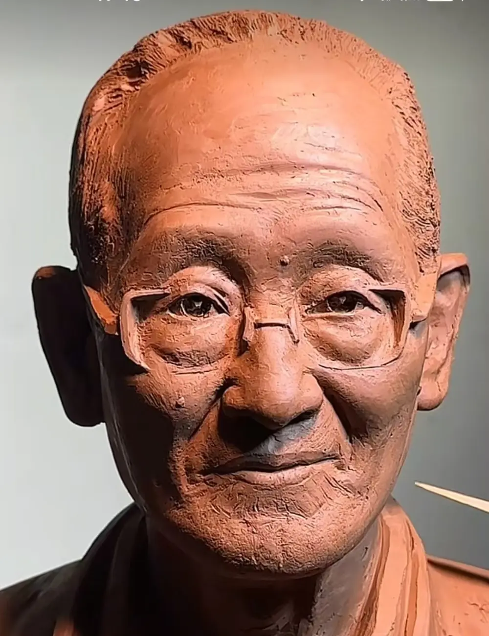 Close-up of the custom memorial bronze bust for an elderly man with glasses, focusing on the lifelike eyes behind the sculpted frames, capturing his gentle, thoughtful expression.