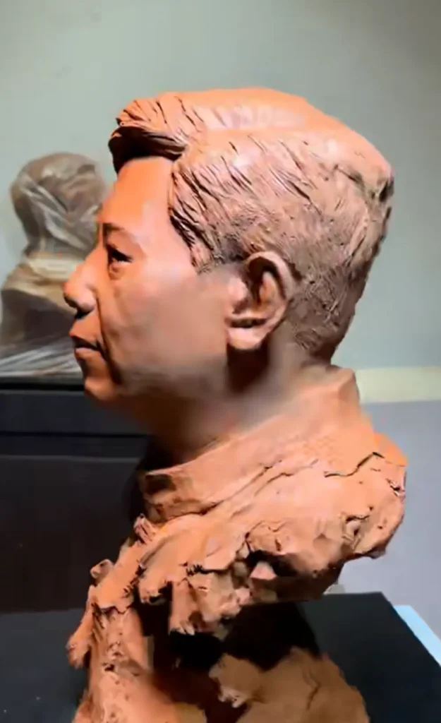 Right profile view of the handcrafted clay bust, showing the natural head shape, hair sculpting, and collar details