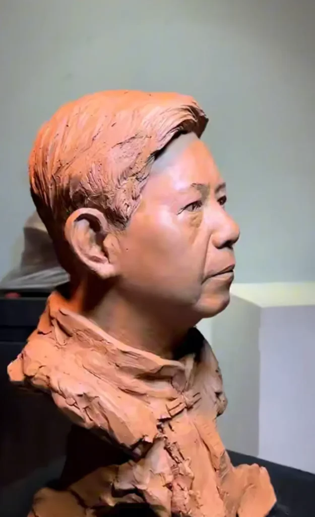 Left profile view of the clay bust, showcasing the sculpted hair texture, ear details, and natural facial structure