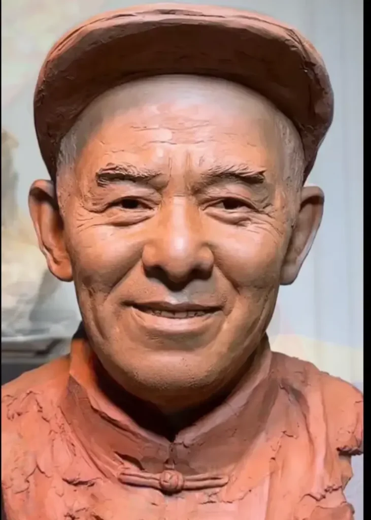Straight-on front view of the finished clay bust, capturing the elderly father’s warm gaze, wrinkles, and traditional clothing details