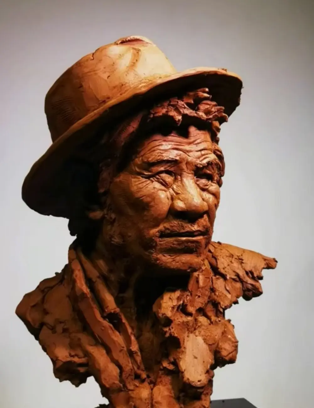 Side view of the hand-sculpted clay memorial bust, showcasing the elderly man’s hat, weathered facial lines, and natural posture